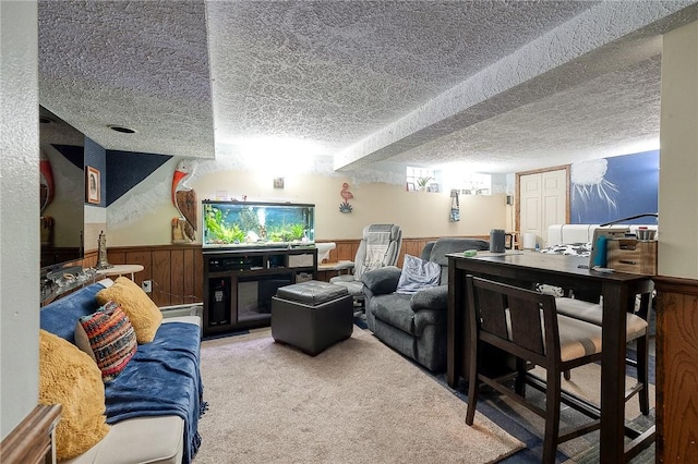 living room featuring wood walls, carpet, a textured ceiling, and wainscoting