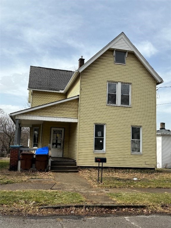 traditional home with covered porch and a chimney