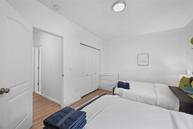 bedroom featuring light wood-style floors, baseboards, and a closet