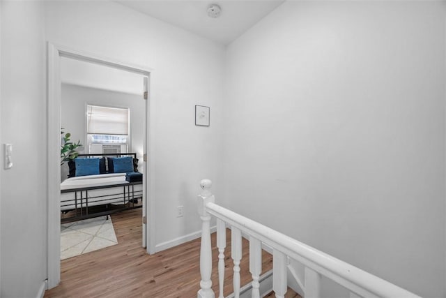 hallway featuring baseboards, an upstairs landing, and wood finished floors