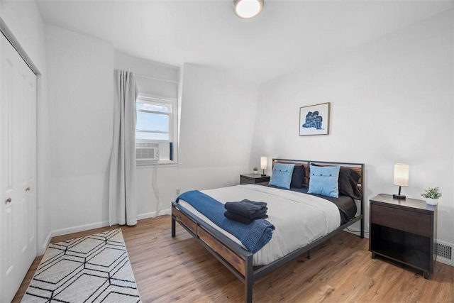 bedroom with visible vents, baseboards, cooling unit, light wood-style floors, and a closet