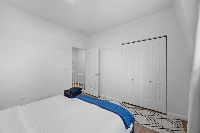 bedroom featuring light wood finished floors, baseboards, and a closet