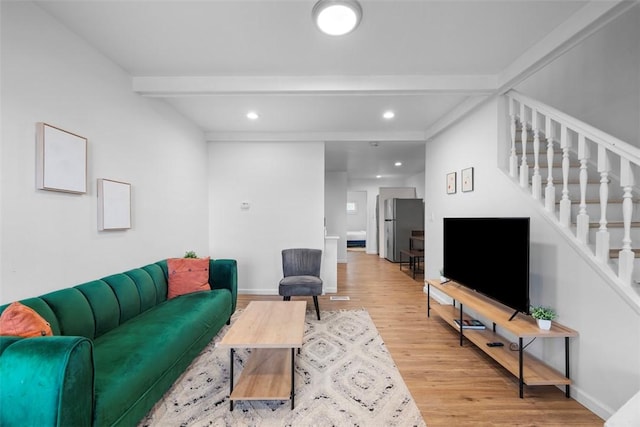 living room featuring beamed ceiling, stairway, baseboards, and wood finished floors