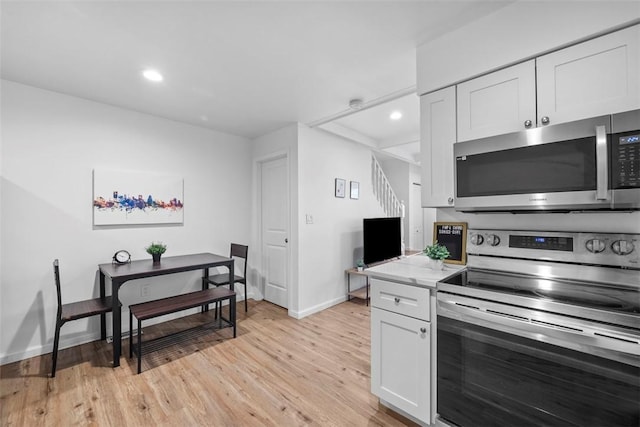 kitchen with light wood-type flooring, appliances with stainless steel finishes, white cabinets, and recessed lighting