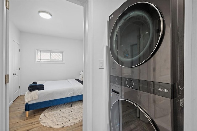 laundry area featuring wood finished floors, stacked washer and clothes dryer, and laundry area