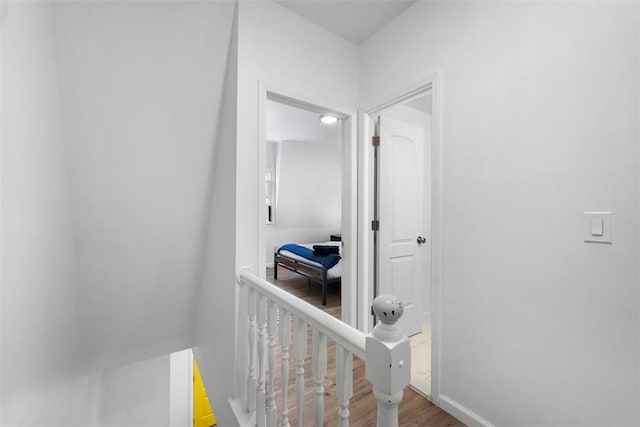 hall featuring baseboards, an upstairs landing, and wood finished floors