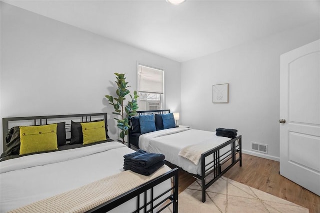 bedroom with light wood finished floors, baseboards, and visible vents