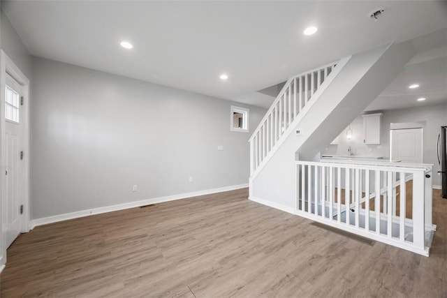 unfurnished room with stairs, baseboards, wood finished floors, and recessed lighting