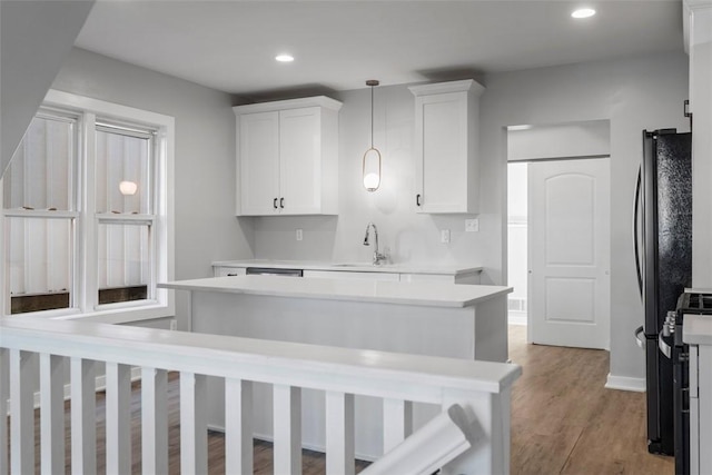 kitchen with light wood-style floors, white cabinets, a sink, and light countertops