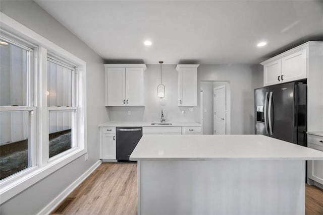 kitchen featuring dishwashing machine, light wood-style flooring, white cabinets, light countertops, and black fridge