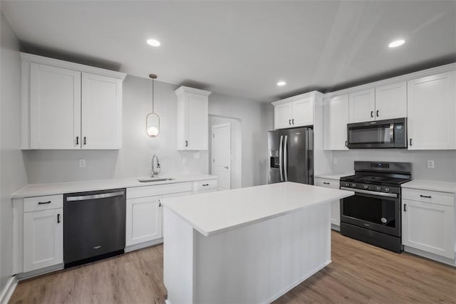 kitchen with light wood finished floors, appliances with stainless steel finishes, white cabinets, and a sink