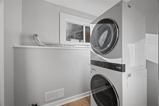 washroom with laundry area, stacked washer / dryer, wood finished floors, and visible vents