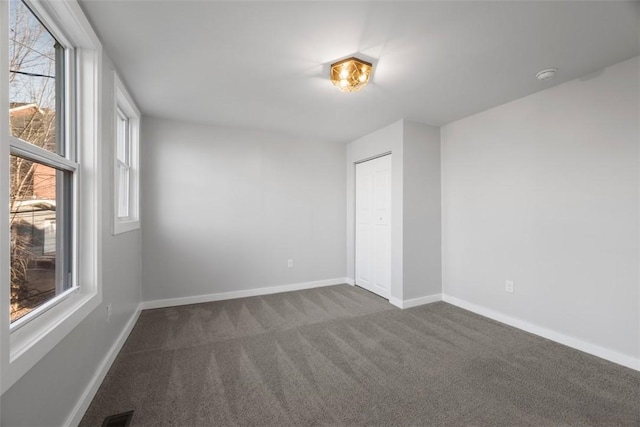 empty room featuring baseboards, visible vents, and dark carpet