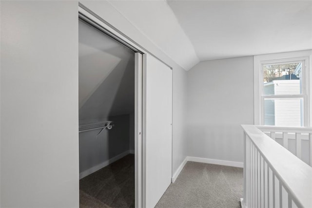 hall with vaulted ceiling, carpet floors, and baseboards