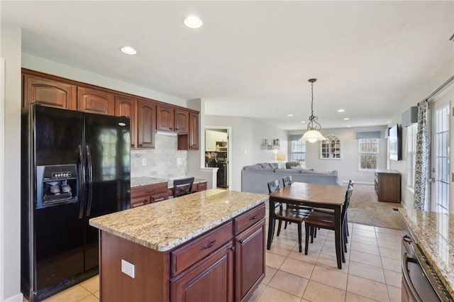 kitchen with decorative backsplash, light stone counters, open floor plan, a center island, and black refrigerator with ice dispenser