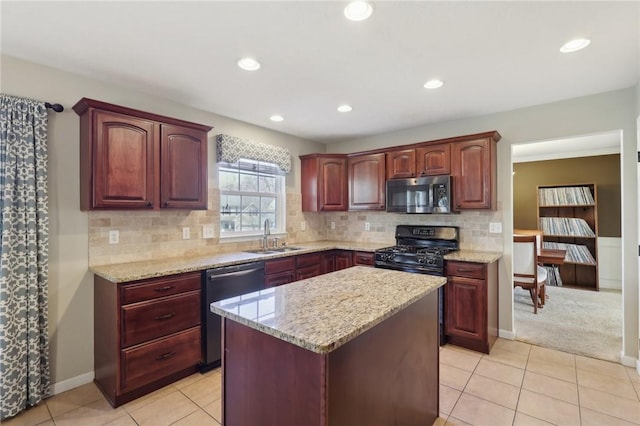 kitchen with appliances with stainless steel finishes, a kitchen island, a sink, and light stone countertops