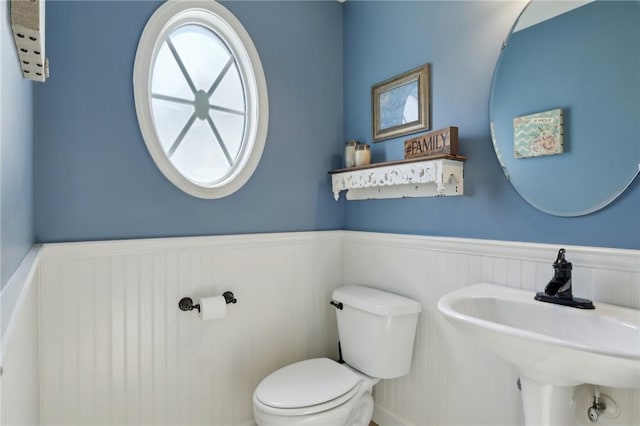 bathroom with toilet, a sink, and wainscoting