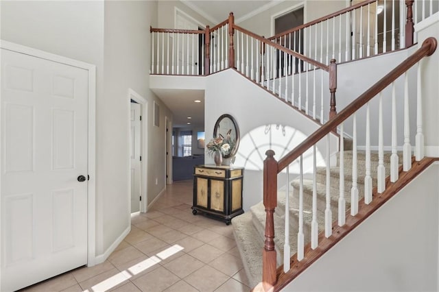 tiled foyer featuring crown molding, a high ceiling, stairway, and baseboards