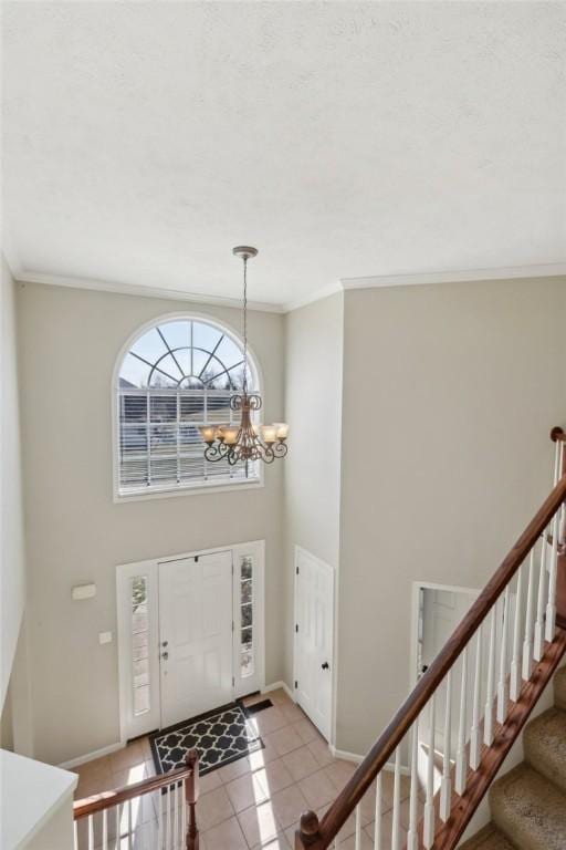 entryway featuring light tile patterned floors, baseboards, stairway, ornamental molding, and an inviting chandelier