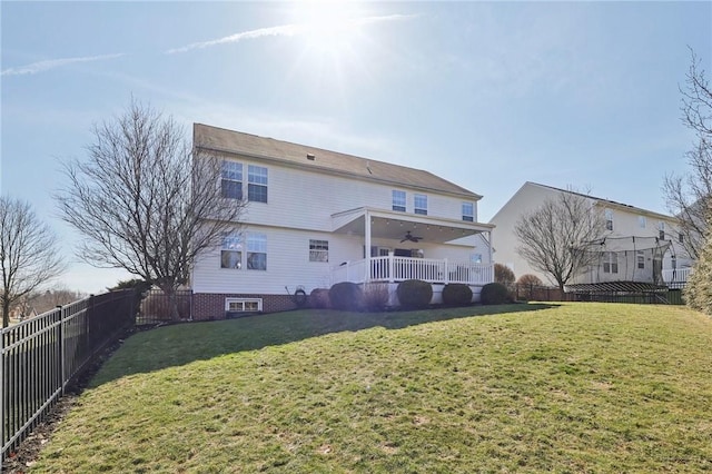 back of property with ceiling fan, a fenced backyard, and a yard