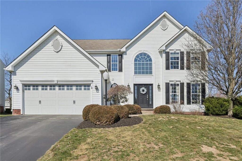 traditional home with a garage, aphalt driveway, and a front yard