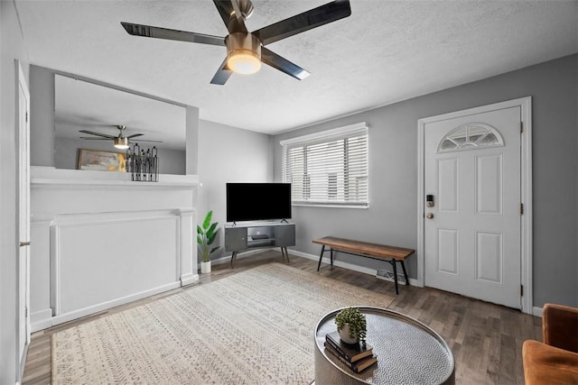 living room with baseboards, a textured ceiling, a ceiling fan, and wood finished floors