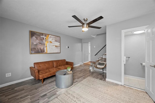 living area with stairs, ceiling fan, baseboards, and wood finished floors