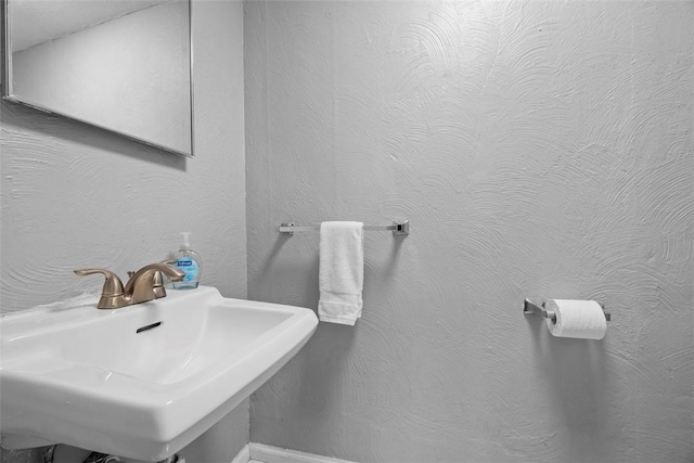 bathroom featuring a textured wall and a sink