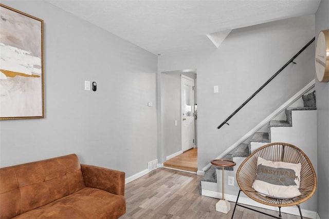 interior space with baseboards, stairs, visible vents, and wood finished floors