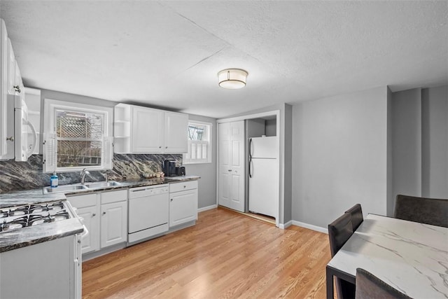 kitchen with white appliances, light wood-style flooring, white cabinets, and decorative backsplash