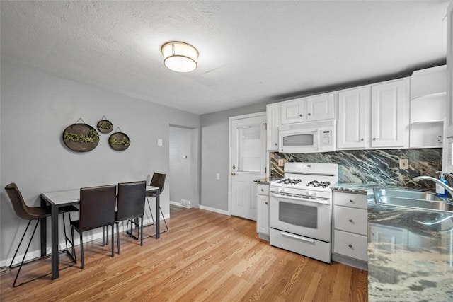 kitchen featuring white appliances, white cabinets, light wood-style flooring, a sink, and backsplash