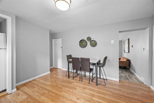 dining area featuring wood finished floors, visible vents, and baseboards