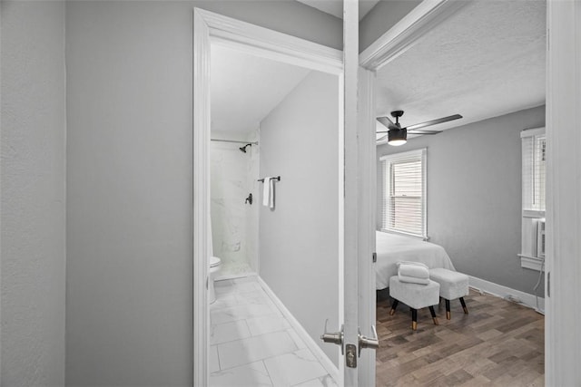 bathroom featuring toilet, a shower stall, baseboards, and ceiling fan