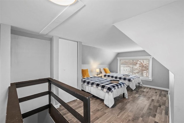 bedroom featuring lofted ceiling, a closet, baseboards, and wood finished floors