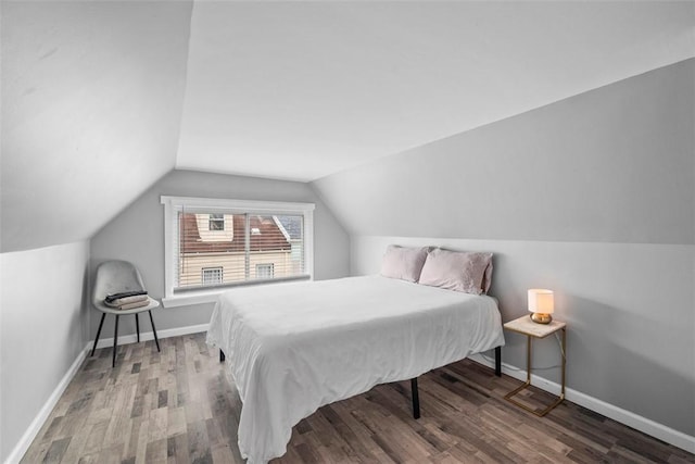 bedroom with vaulted ceiling, wood finished floors, and baseboards