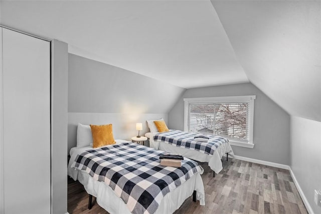 bedroom with lofted ceiling, baseboards, and wood finished floors