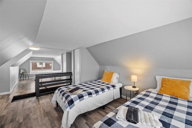 bedroom featuring lofted ceiling, baseboards, and wood finished floors