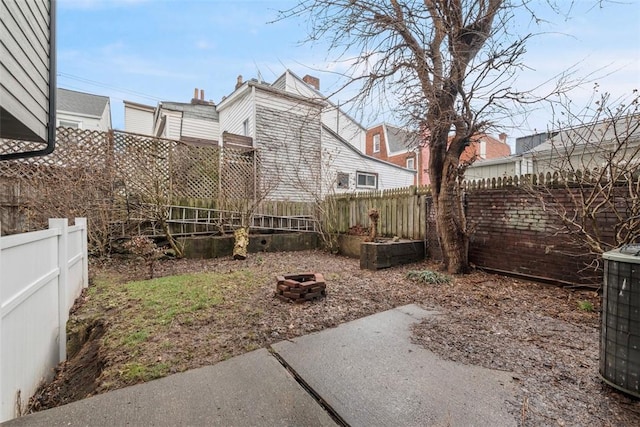 view of yard with an outdoor fire pit, cooling unit, and a fenced backyard