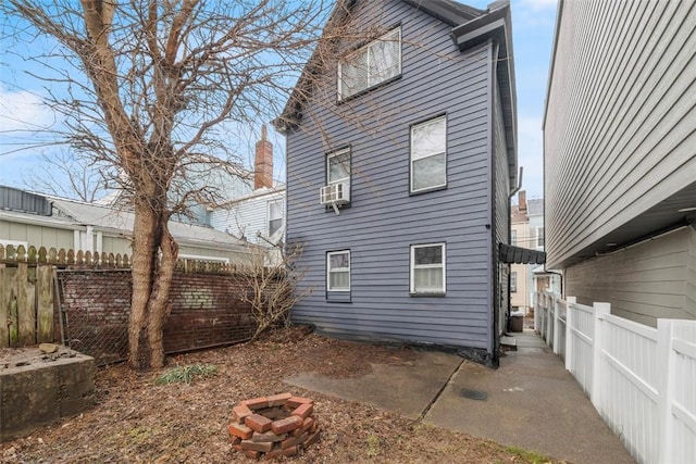 back of property featuring cooling unit, a fenced backyard, a patio, and a fire pit