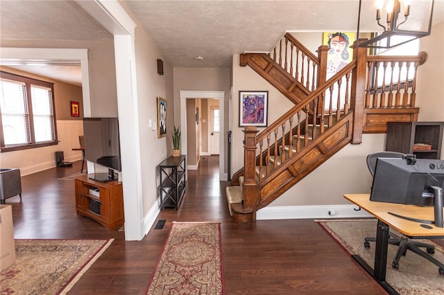 entryway featuring a textured ceiling, wood finished floors, visible vents, and baseboards