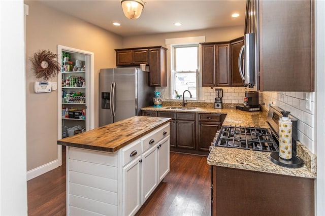 kitchen featuring stainless steel appliances, butcher block counters, dark wood-type flooring, and a sink