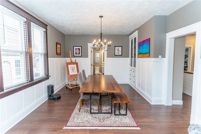 dining room with dark wood-style floors, wainscoting, a notable chandelier, and a textured ceiling