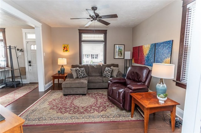 living room with ceiling fan, baseboards, and wood finished floors