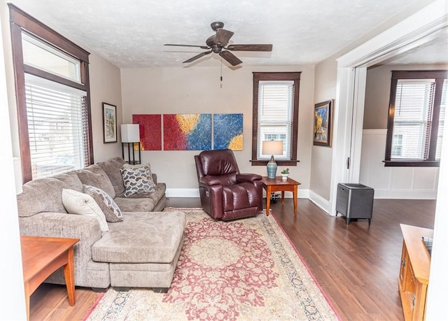 living area with ceiling fan, plenty of natural light, a textured ceiling, and wood finished floors