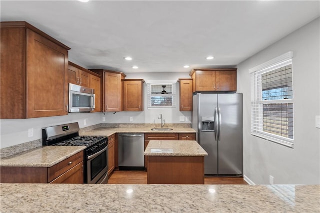 kitchen featuring appliances with stainless steel finishes, light stone counters, a sink, and recessed lighting