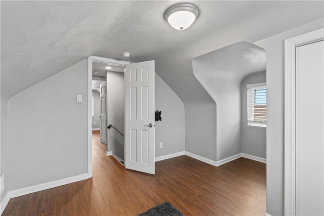 additional living space featuring baseboards, vaulted ceiling, and wood finished floors