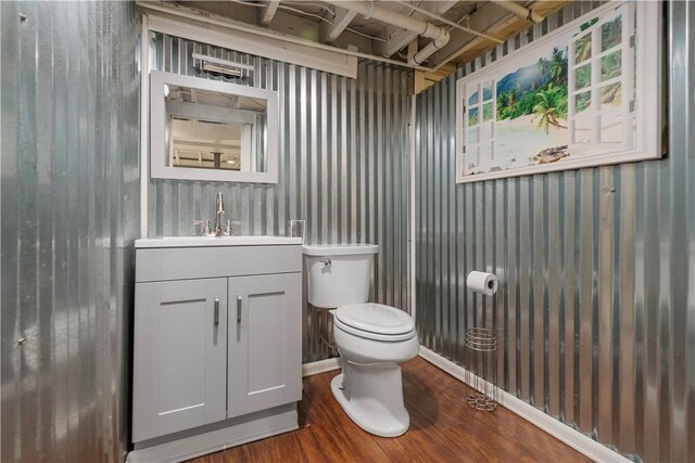 half bathroom with wood finished floors, vanity, and toilet