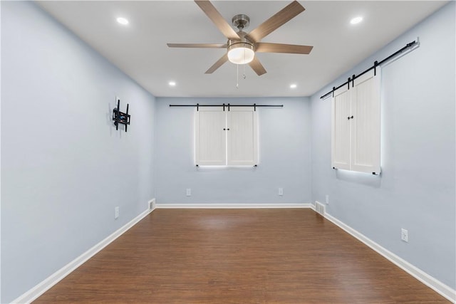 unfurnished room featuring recessed lighting, ceiling fan, baseboards, and a barn door