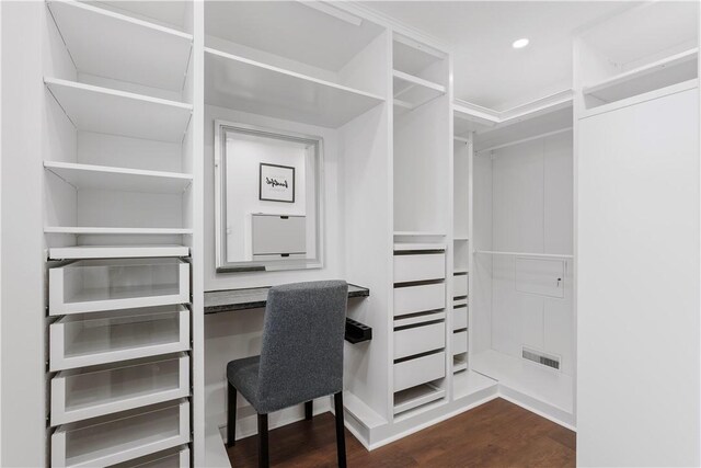 spacious closet with visible vents, dark wood finished floors, and built in study area