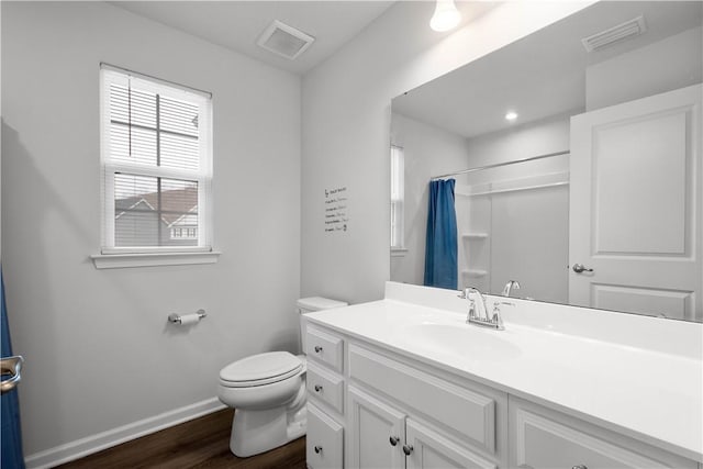 full bath featuring toilet, vanity, visible vents, and baseboards